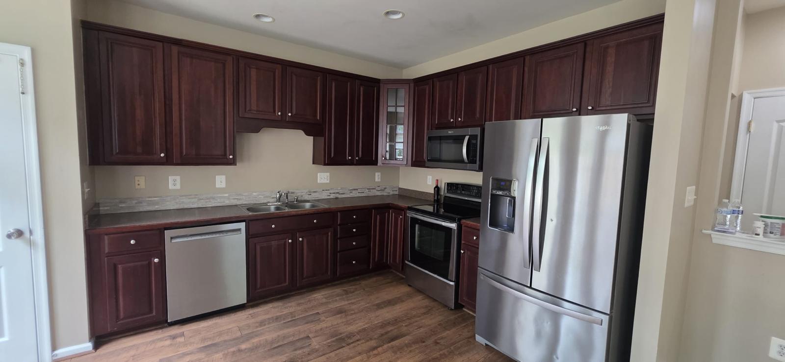 A freshly cleaned kitchen with dark wood cabinetry and clear counters